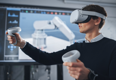 Ingenieur Student trägt Virtual-Reality-Headset, hält Joysticks und steuert bionische Gliedmaßen, während Aktionen auf dem Bildschirm