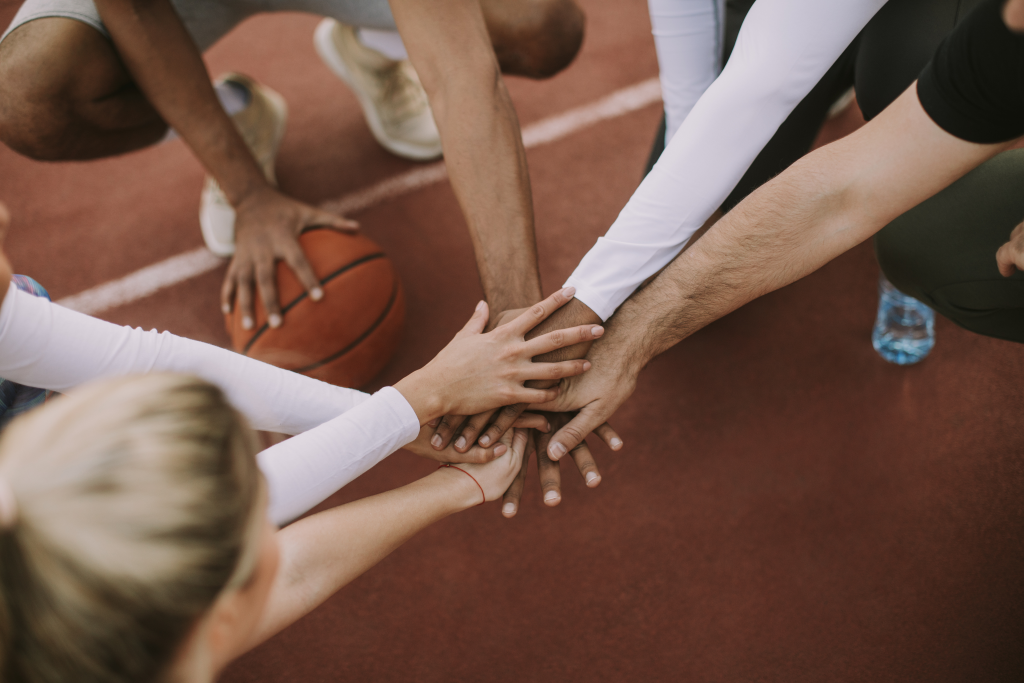 Sportler auf der Leichtathletikbahn legen Hände zusammen